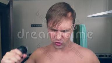 一个有趣的帅哥在浴室里用电动剃须刀刮胡子，在镜子前唱歌。 4k.